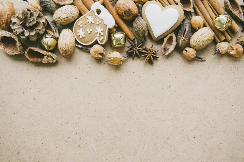 Border of cinnamon sticks, nuts, star anise and iced biscuits on kraft paper