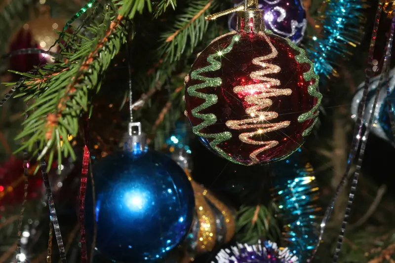 Boules de Noël bleue et rouge et guirlandes scintillantes dans les branches d'un sapin