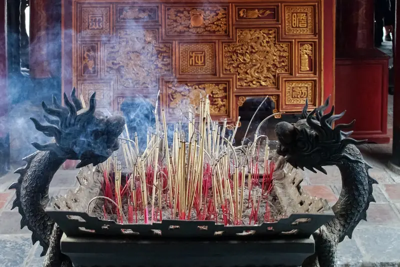 Dragon-decorated bronze incense burner full of smoking sticks in Hanoi