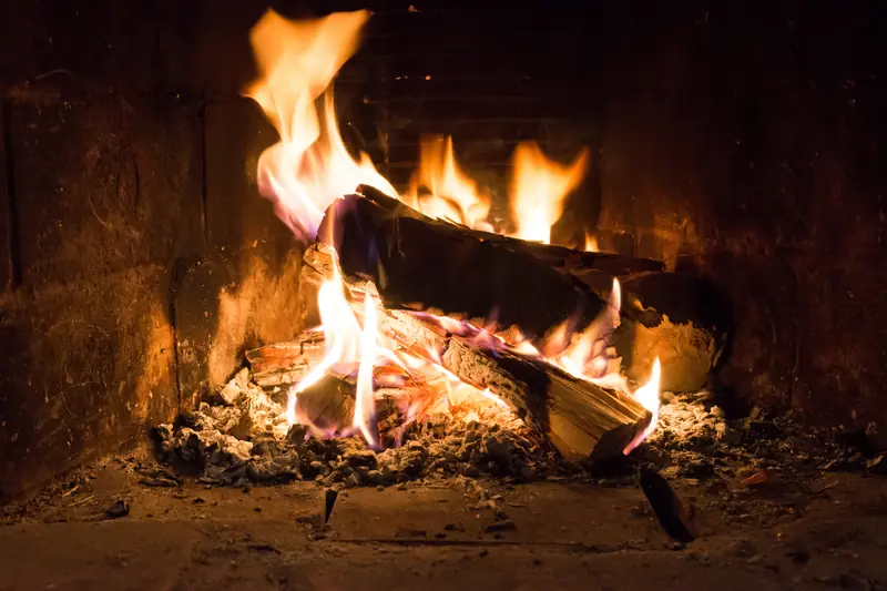 Bûches qui flambent dans l'âtre d'une cheminée, braises rougeoyantes