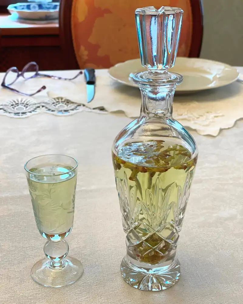Carafe en cristal et petit verre de liqueur claire aux bourgeons de cassis sur une nappe