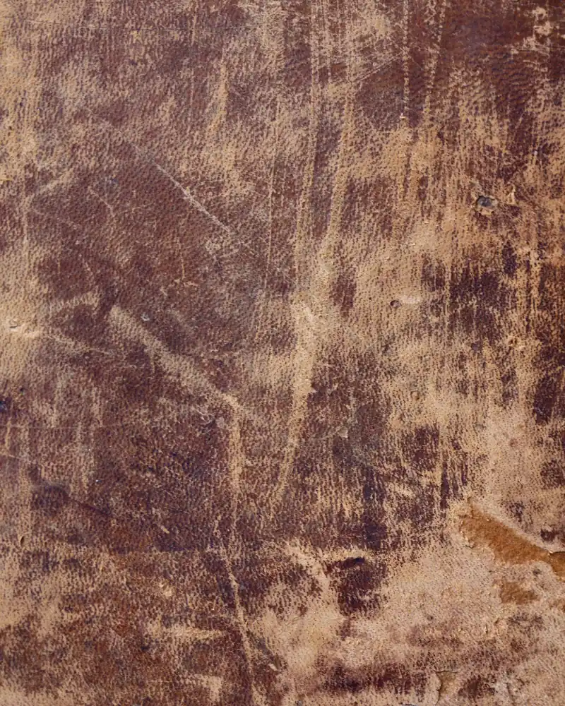 Couverture de livre ancienne en cuir brun usé, rayée et tachée