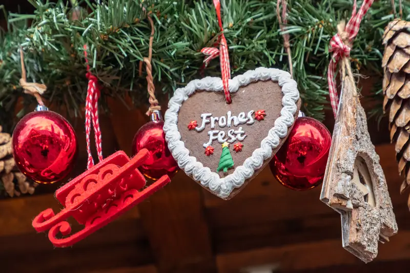 Cœur en pain d'épices « Frohes Fest » et boules rouges suspendus à des branches de sapin