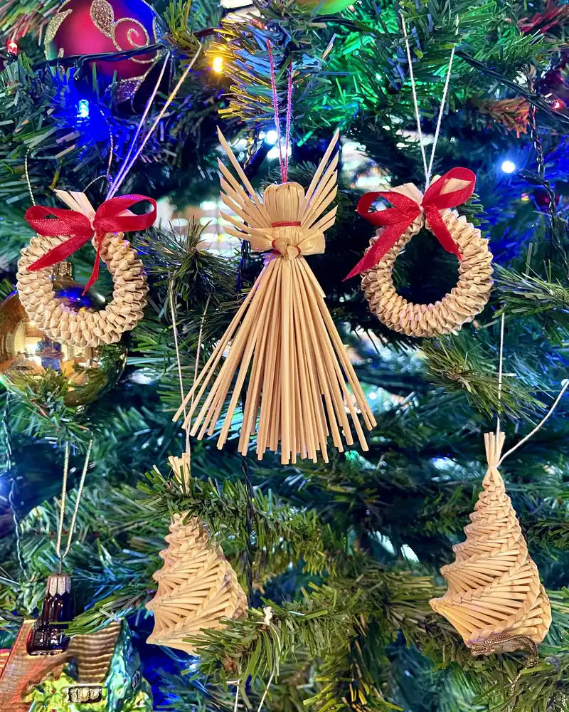 Straw decorations, an angel and wreaths, hanging in a Christmas tree