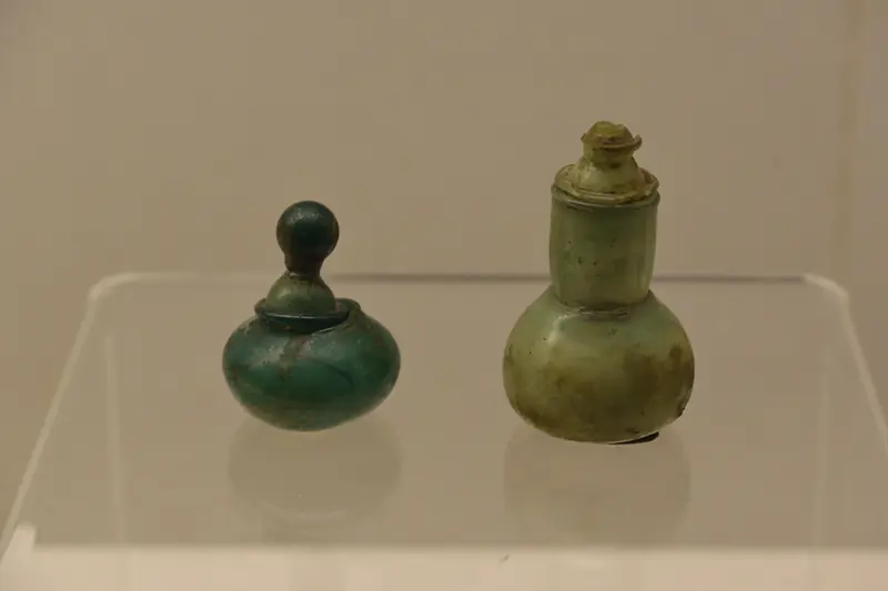 Two small antique green stone perfume bottles displayed in a museum case