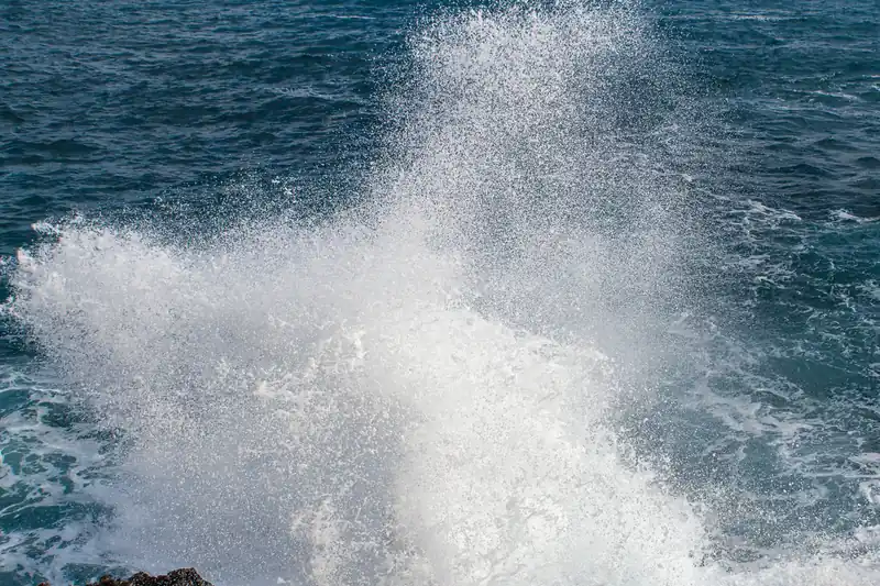 Sea spray lifted by the wind above the rocks of a cove in Mallorca