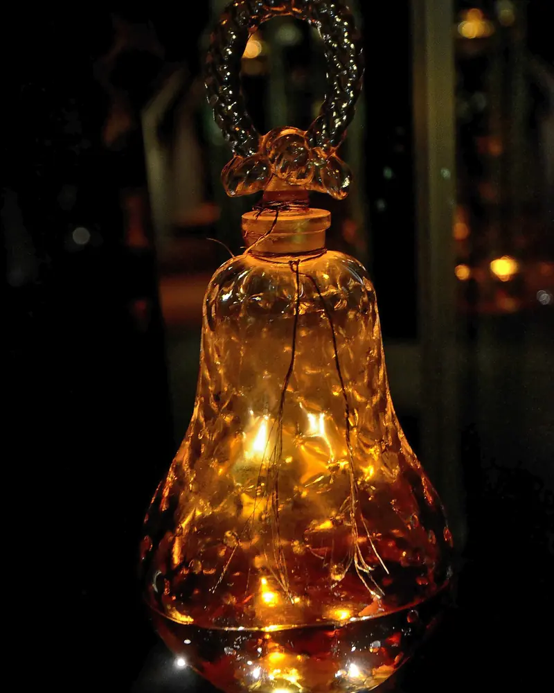 Bell-shaped amber crystal perfume bottle lit up in a dark display case