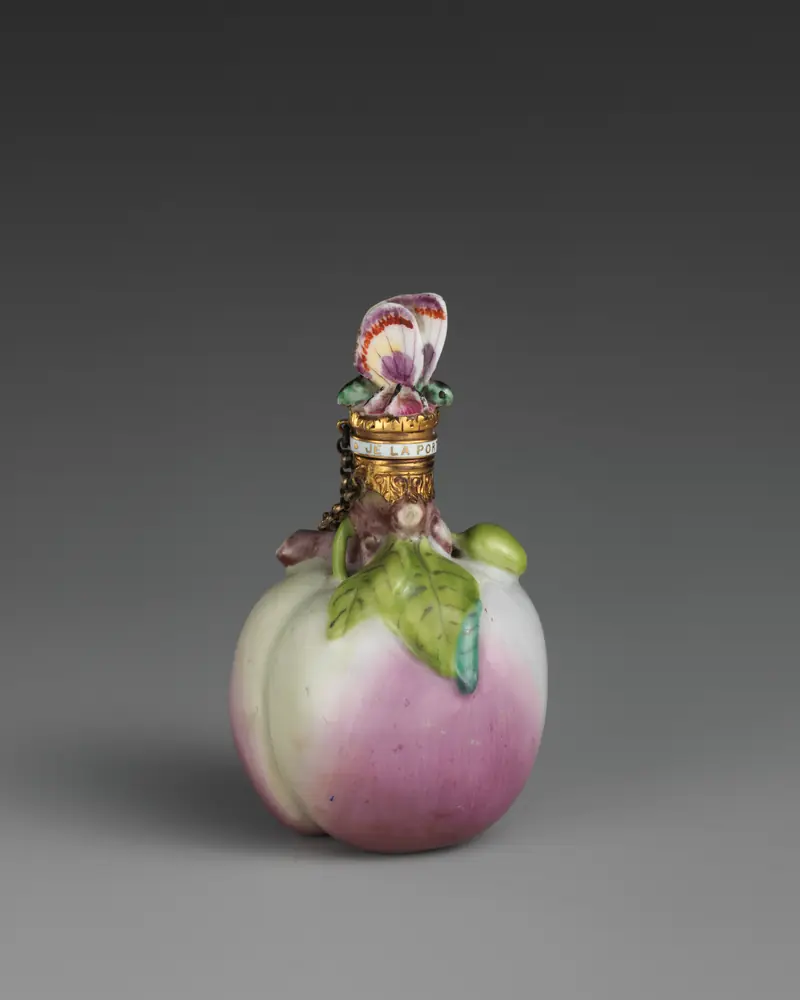 Flacon de senteur en porcelaine en forme de pêche rose surmontée de fleurs