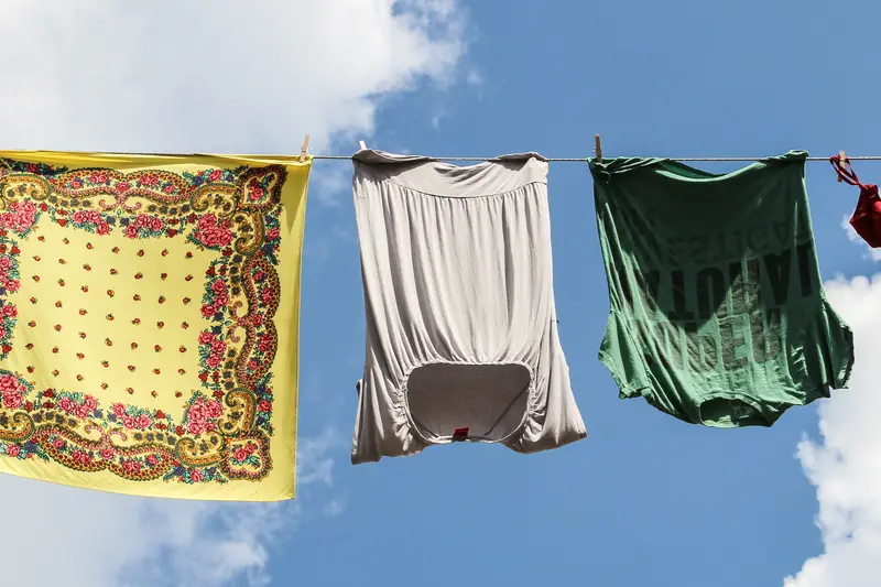 Foulards et vêtements suspendus à une corde à linge sous un ciel bleu nuageux