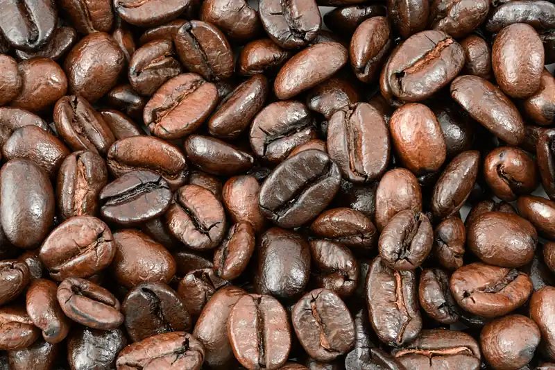Grains de café torréfiés brun foncé et brillants qui remplissent tout le cadre