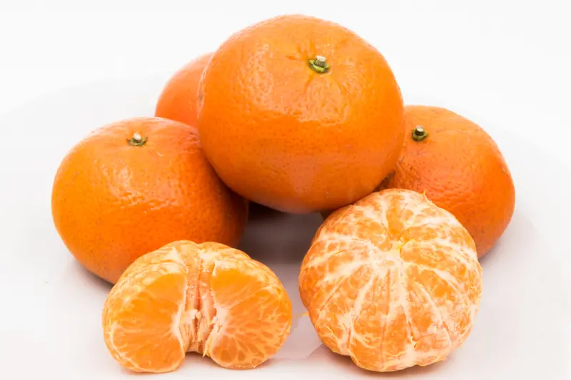 Whole mandarins and two peeled fruits showing their segments, on a white background