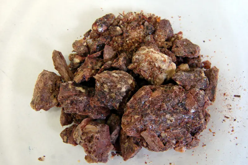 Morceaux de benjoin de Sumatra brun rouge et ambrés en petit tas sur fond blanc