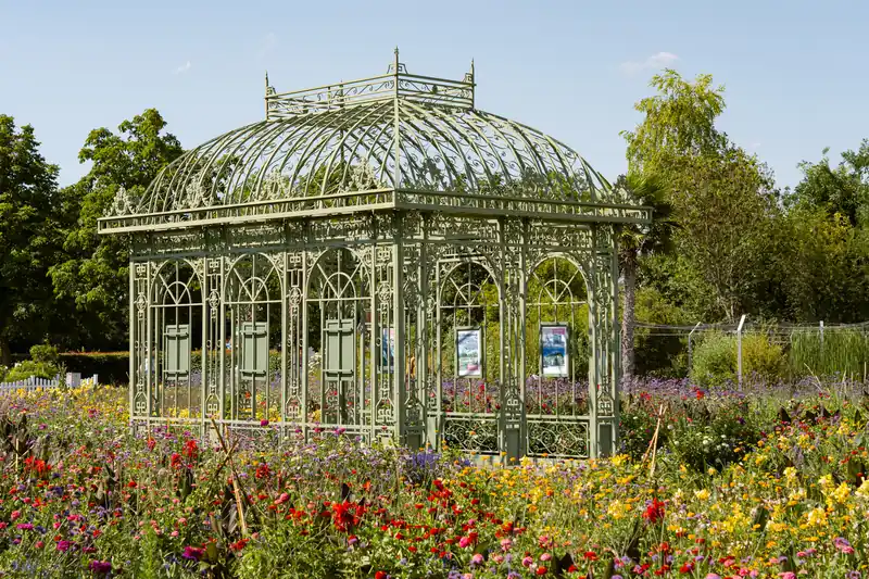 Glass and wrought-iron pavilion surrounded by colourful summer flower beds in Vienna