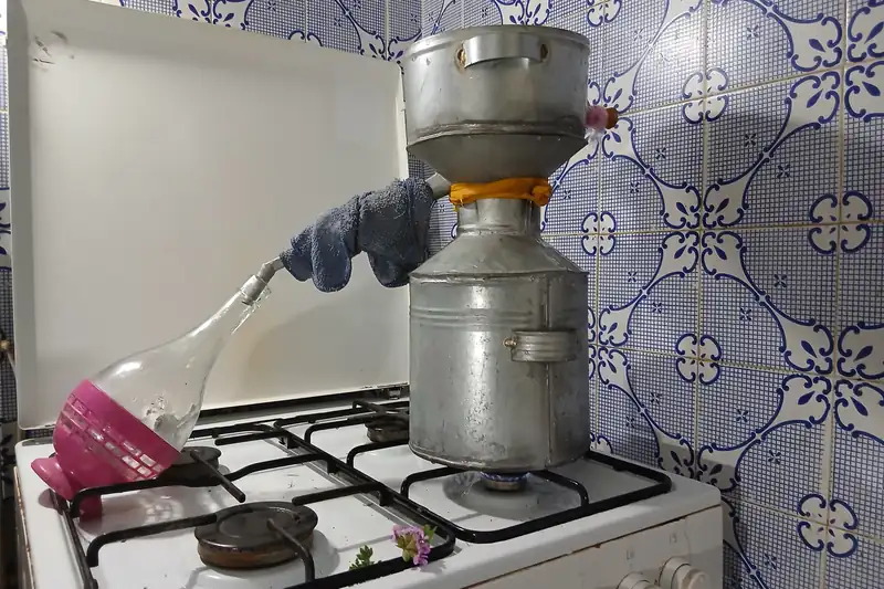 Small still on a gas stove, geranium water flowing into a glass flask