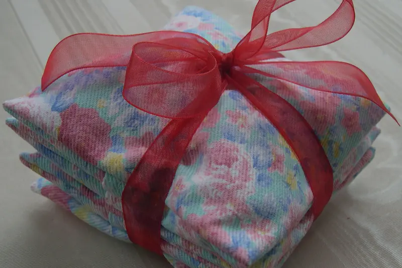 Pile de sachets de lavande en tissu fleuri noués d'un ruban d'organza rouge