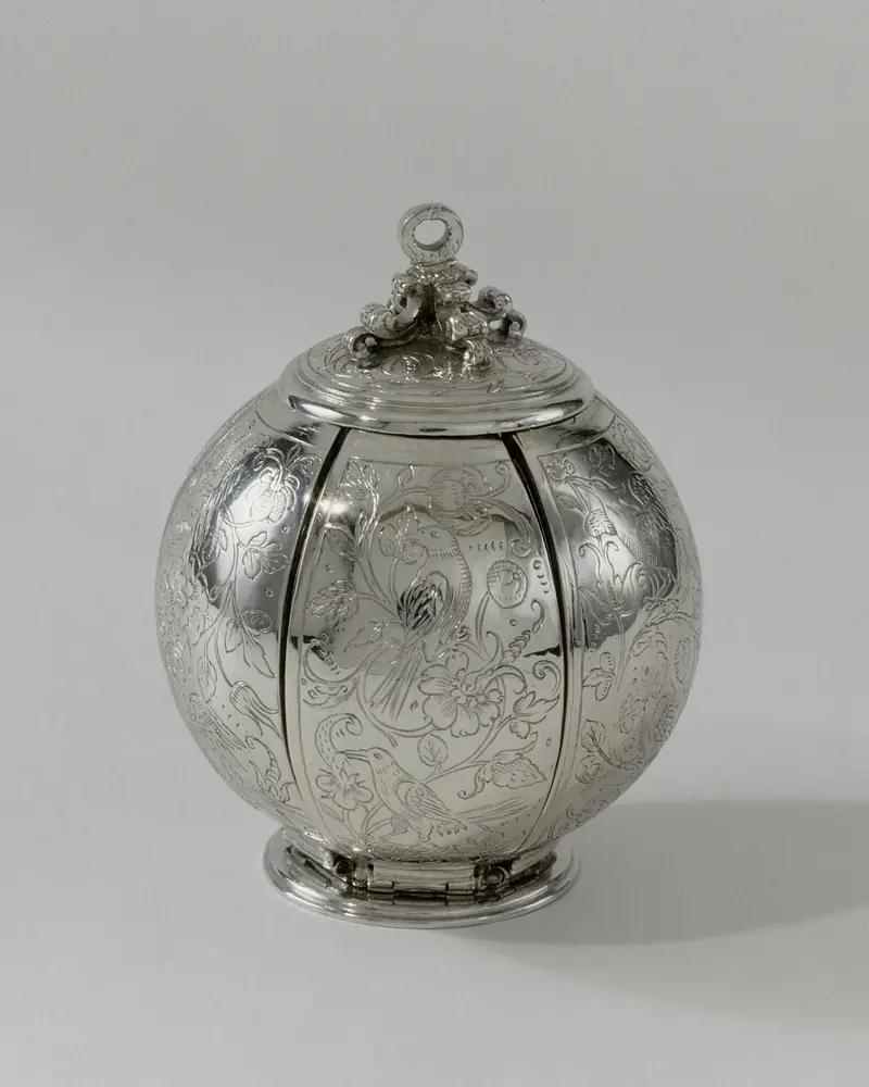 Pomander ancien en argent ciselé en forme de boule à côtes, sur fond gris clair