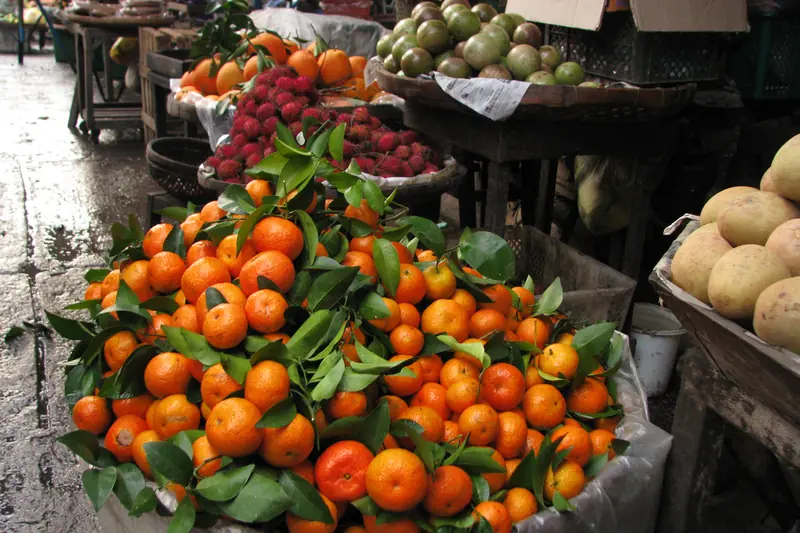 Pyramide d'oranges avec leurs feuilles sur un étal de marché au Vietnam