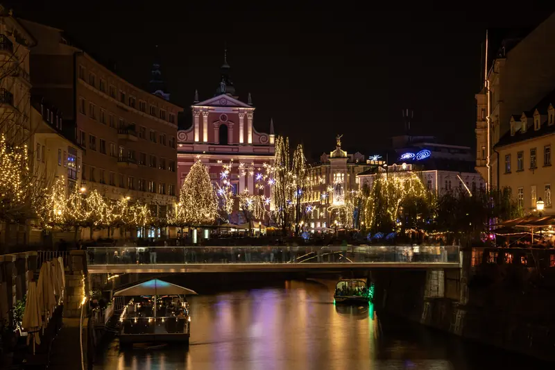 Ljubljana's embankments lit up for the holidays, golden reflections in the river at night