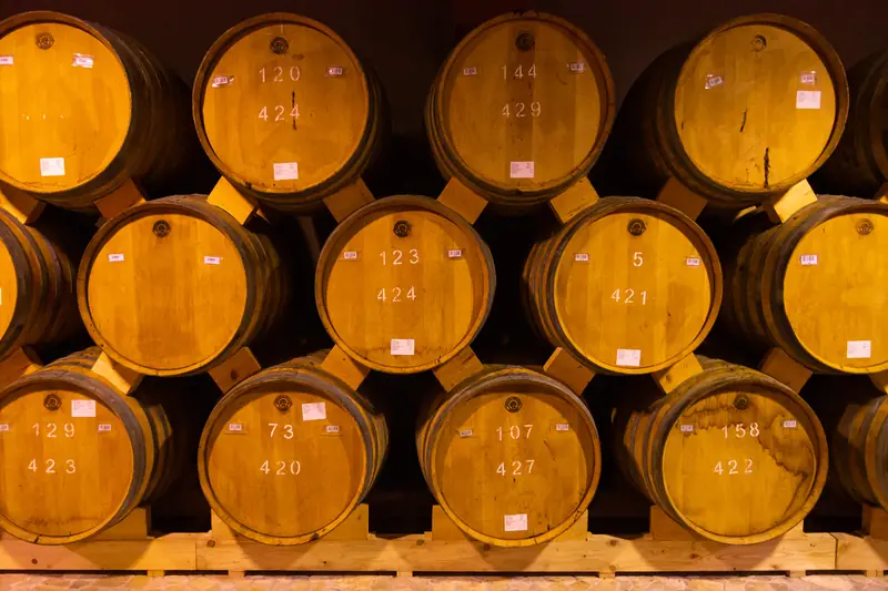 Rows of numbered oak brandy barrels resting in a vaulted cellar in Yerevan