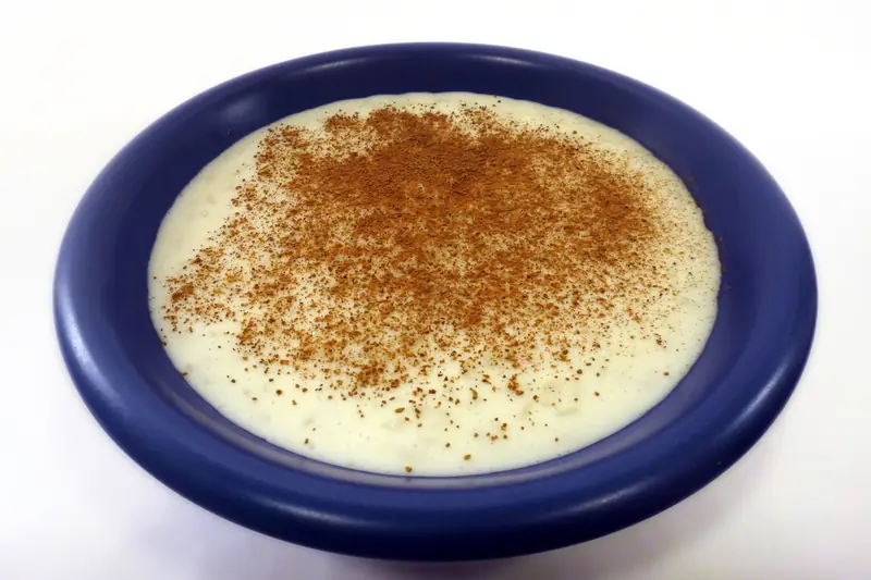 Swedish rice pudding dusted with ground cinnamon in a blue ceramic dish