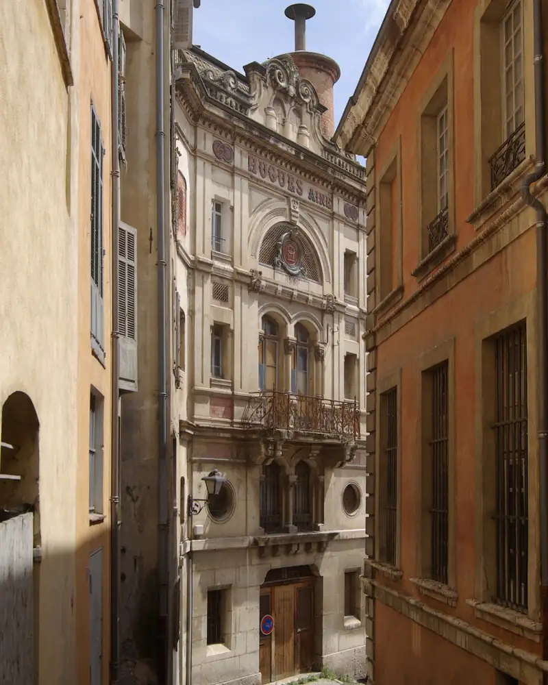 Rue étroite de la vieille ville de Grasse entre des façades ocre et une maison à balcon