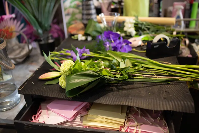 Tiges de fleurs fraîches et feuillages étalés sur l'établi d'un fleuriste