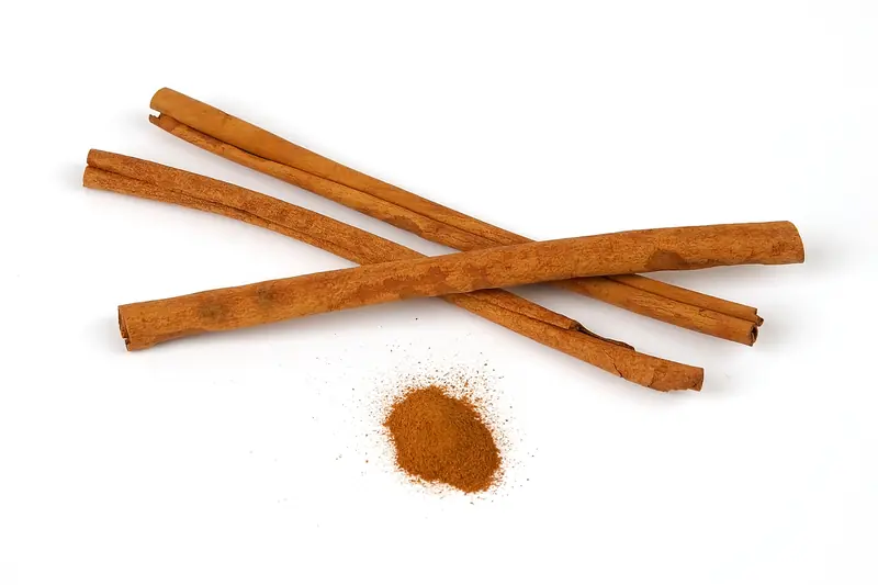 Three crossed cinnamon sticks above a small heap of ground cinnamon