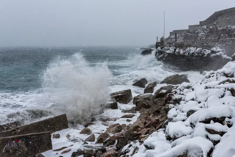 Vagues grises frappant une côte enneigée près de Sète un jour de tempête