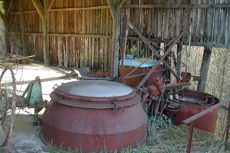 Vieil alambic à lavande en fonte rouillée abandonné sous un hangar de bois