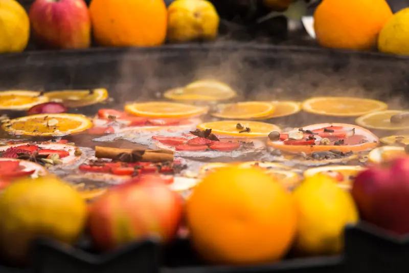 Steaming mulled wine in a wide pan, orange slices, cinnamon and star anise on top